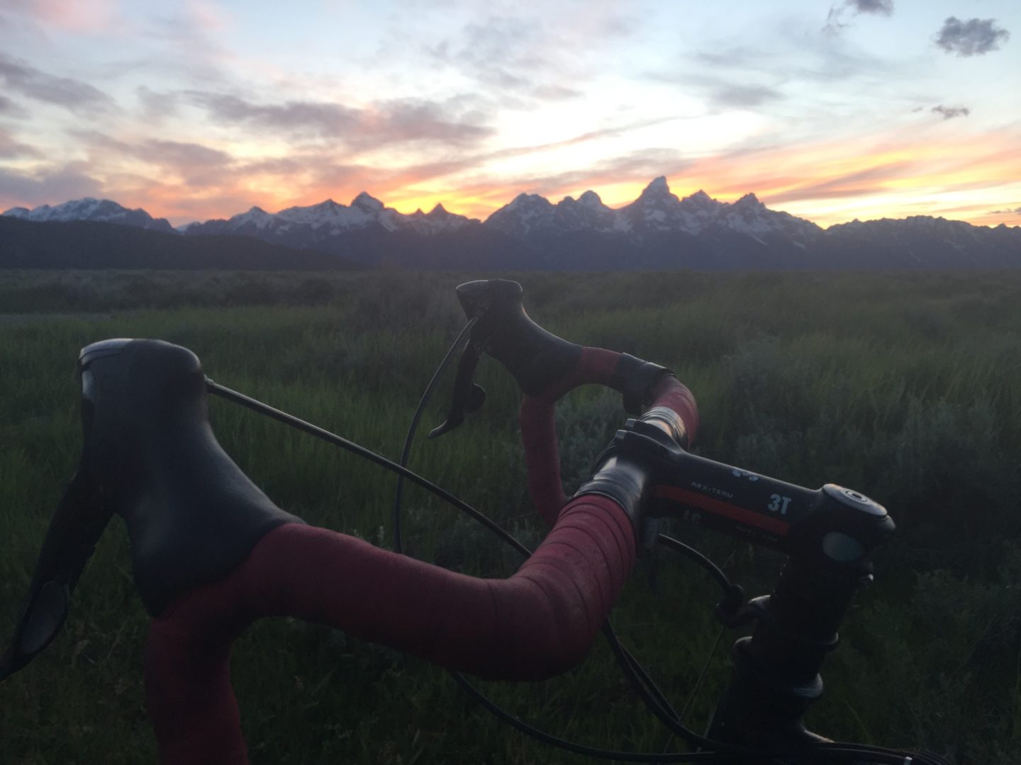 A Bicyclist Pauses In Front Of The Grand Teton Range During A Commute Home From Work