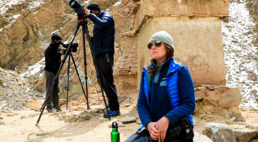 three people watching snow leopards in the himalayas