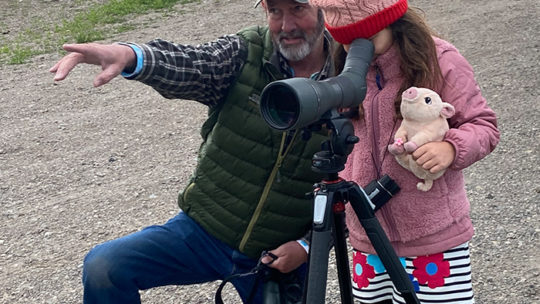 Professional Guide Jeffrey Meehan Instructs A Small Wildlife Enthusiast On What She Is Viewing In The Distance Through A Spotting Scope While On Safari In The Greater Yellowstone Ecosystem