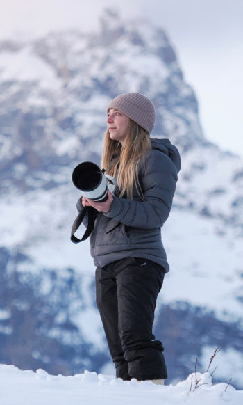 Jackson Hole Wildlife Safari Guide Tiffany Taxis Holds Her Camera As She Stands Outside In The Snow In The Greater Yellowstone Ecosystem