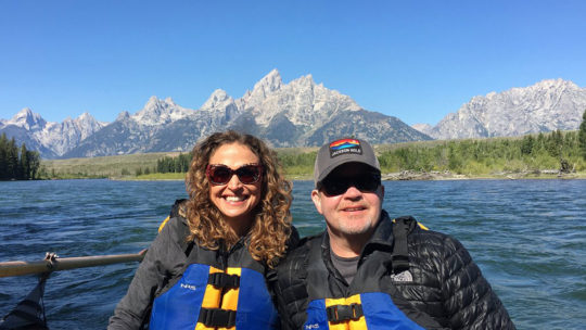 Two Guests Pose In Front Of The Grand Teton Range While Enjoying A Scenic Float Trip In Grand Teton National Park